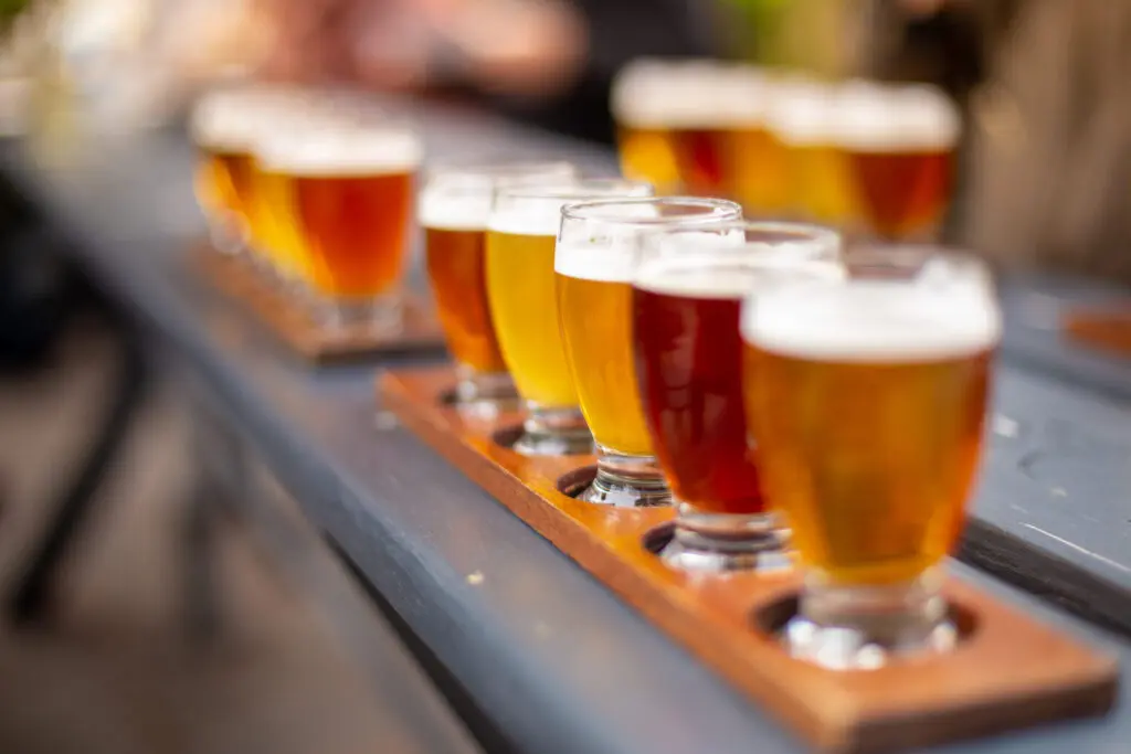 Flight of 5 different beer samples arranged on a wooden paddle